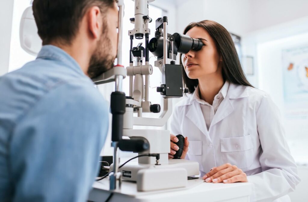 A female eye doctor is performing a slit exam during a comprehensive eye exam for a male patient.