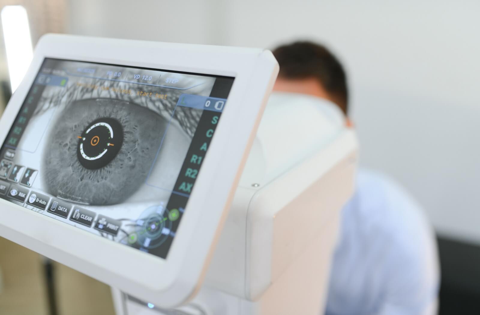 The handsome young man is checking eye vision in a modern ophthalmology clinic.