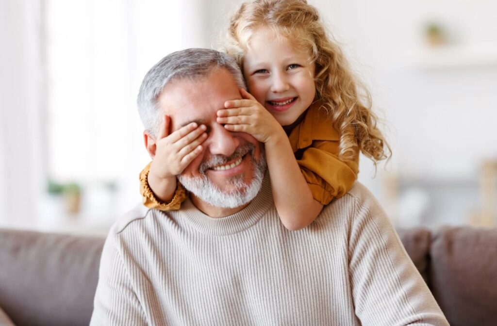 A granddaughter covers the eyes of her grandfather, who wears soft contact lenses to maintain his active lifestyle.