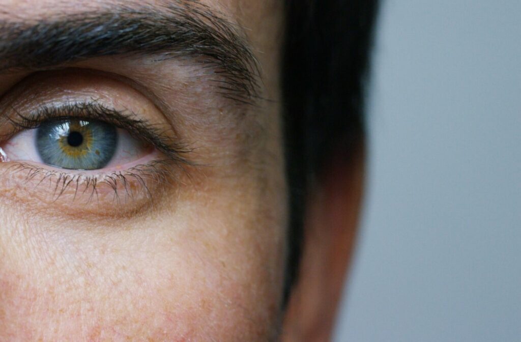 A close-up image of an adult's blue left eye in front of a gray background.