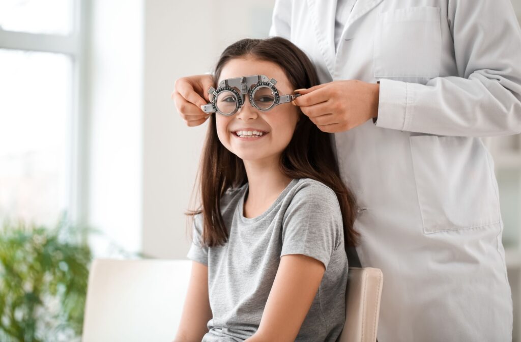 Young girl smiling at the camera while undergoing an eye exam for myopia assessment.