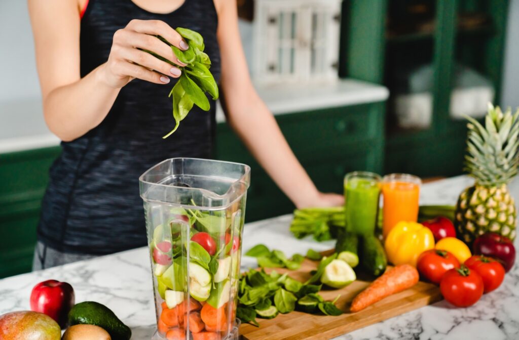 A photo of a person in their kitchen making a smoothie with fruits and vegetables that are high in vitamins.