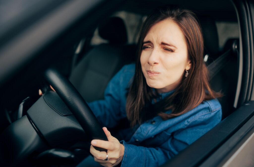 Someone squints to try to see clearly while driving home after an eye exam.