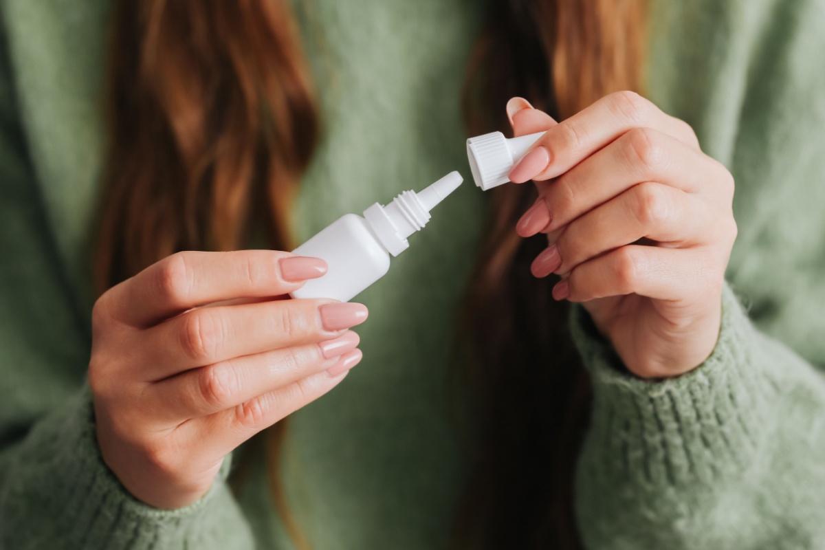 A person opening a bottle of eye drops